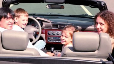 Ebeveynler ve çocuklar cabriolet oturmak ve geriye bakmak o zaman çevirmek