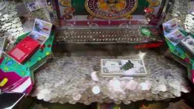 Play machine with many coins and dollars inside, closeup view