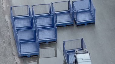 Yükleyici kafes kutusunu taşır ve diğer yakın asfalt koymak