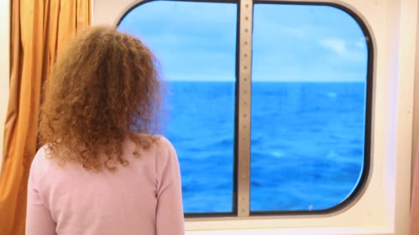 Vrouw in cabine van schip kijkt uit raam op golven — Stockvideo