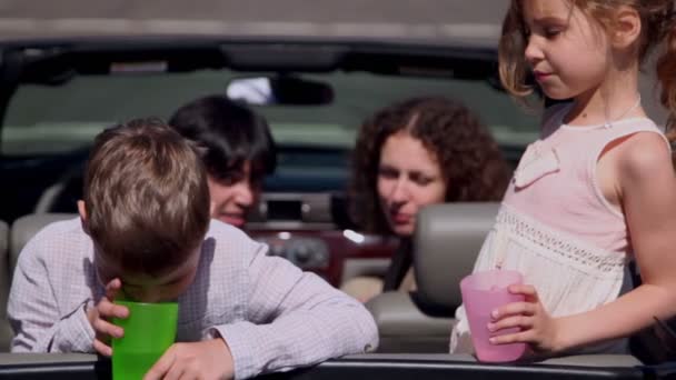 Parents sit in cabriolet and watch their kids with glasses — Stock Video