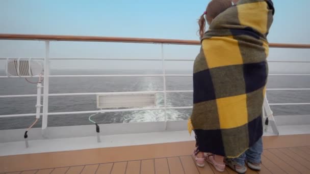 Kids wrapped in plaid stand on deck and admire seascape — Stock Video