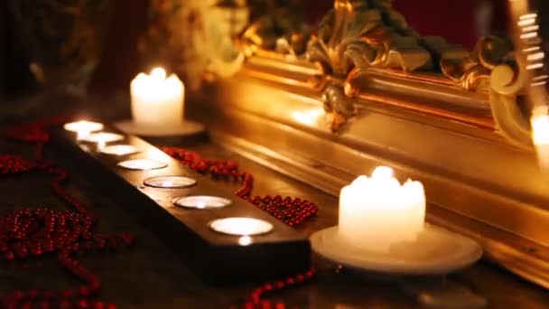 Candele ardenti e perline specchio viso in cornice intagliata nel buio — Video Stock