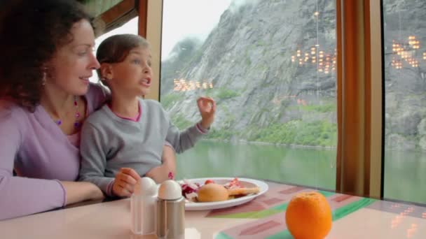 Mother and daughter sit at table with food and watch mountain — Stock Video