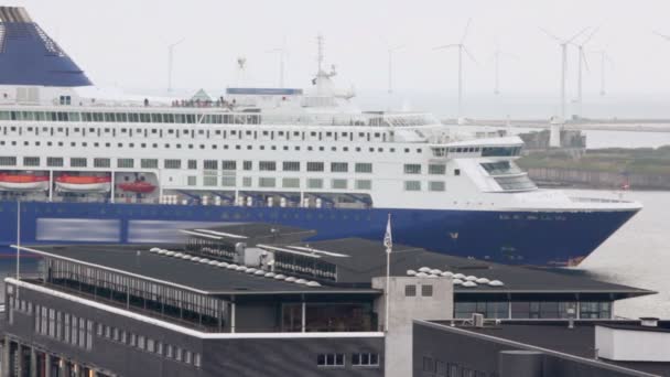 Enorma liner flyter i hamn på bakgrund av väderkvarnen i havet — Stockvideo