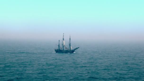 Segelbåt flyter genom vågiga havet ytbehandlar långt bort under blå himmel — Stockvideo