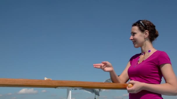 Mulher alimenta várias gaivotas de pão e rir no dia ensolarado — Vídeo de Stock