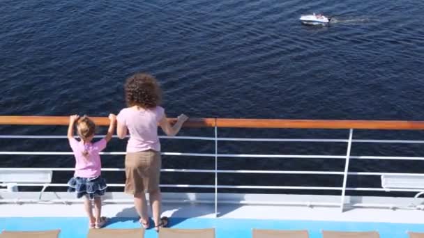 Mother and daughter stand on deck of ship looking at boat — Stock Video