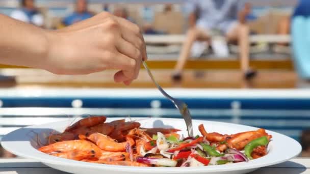 Plato con gambas y ensalada en la mesa frente a la piscina — Vídeo de stock