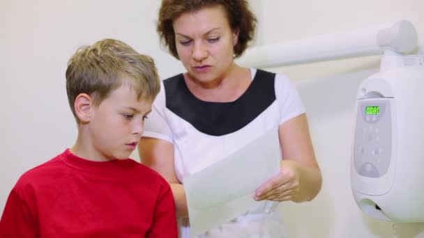 Doctor shows x-ray image for little boy and speak with him — Stock Video