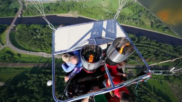 Пассажиры летают в воздушной корзине над рекой и лесом — стоковое видео