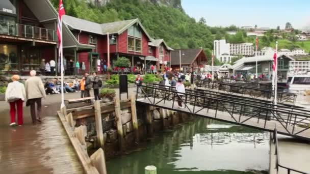 Muchos turistas caminan en el muelle del pueblo costero en el día de primavera — Vídeo de stock