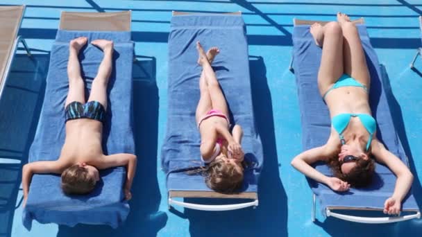 Mother, daughter and son sunbathe in chaise lounges on deck ship — Stock Video