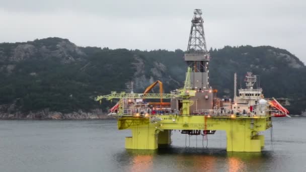 Equipamento de petróleo localizado no mar perto da costa com floresta na montanha — Vídeo de Stock