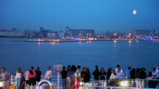 Many people on deck of ship which floats near coastal city — Stock Video