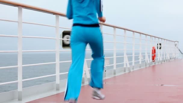 Женщина в синем бежит по палубе плавучего корабля вдоль борта — стоковое видео