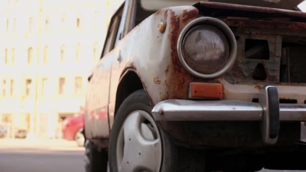 Old rusty car stand on street with traffic at sunny day — Stock Video