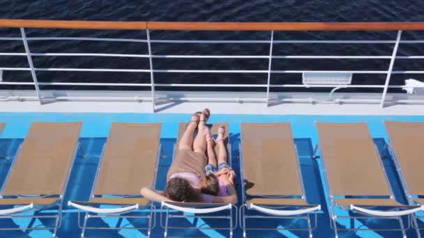 Mère avec fille se trouvent dans chaise longue sur le pont doublure 