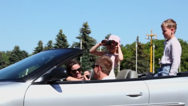 Pareja con niños sentarse en cabriolet, chica mira a través de binocular — Vídeo de stock