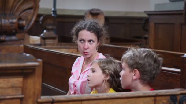 Mutter erzählt Kindern von Religion, wenn sie in der Kirche sitzen — Stockvideo