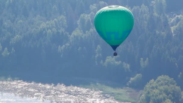 Balon zielony kolor leci daleko nad rzeka i drewna — Wideo stockowe