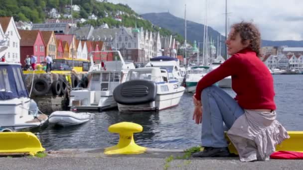 Mujer se sienta y canta en muelle en el muelle de la ciudad costera de Bergen — Vídeo de stock