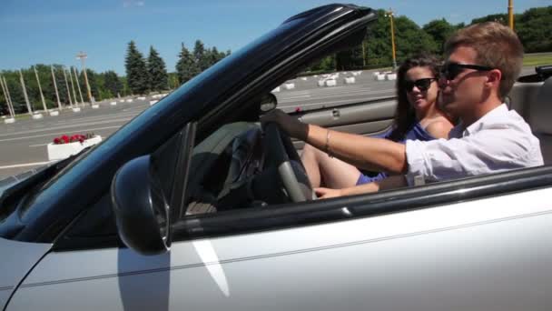 Young couple sit in cabriolet and ride by road at sunny day — Stock Video