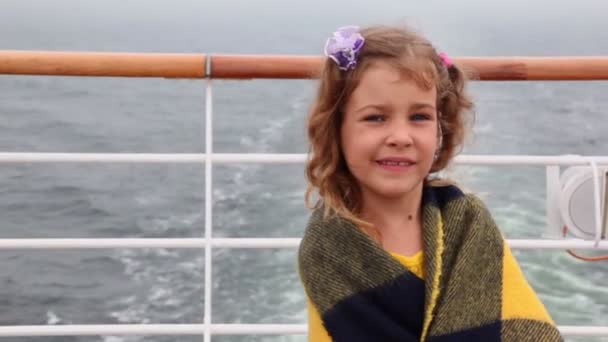 Little girl wrapped in plaid stands on deck during cruise — Stock Video