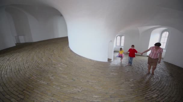 Madre con dos hijos camina en corredor espiral con suelo pavimentado — Vídeos de Stock