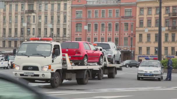 Инспектор полиции стоит рядом с двумя аварийными грузовиками с машинами — стоковое видео
