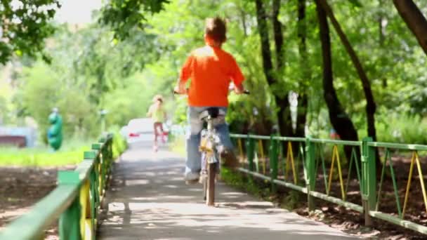 Niña monta en scooter y su hermano conduce bicicleta — Vídeos de Stock