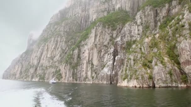Touristic vessel floats by fiord near rocky cliff at fiord — Stock Video