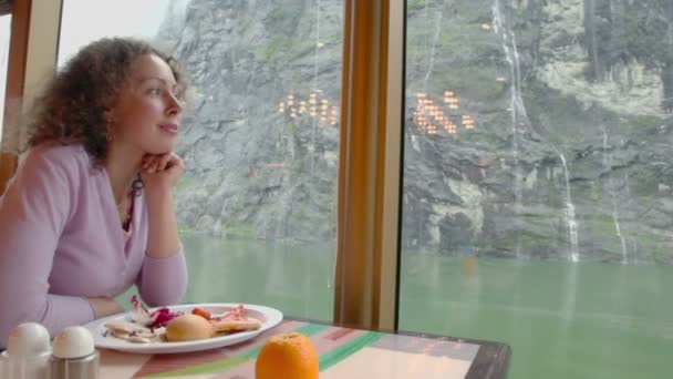 Femme assise à table avec de la nourriture et regarder la cascade sur la montagne — Video