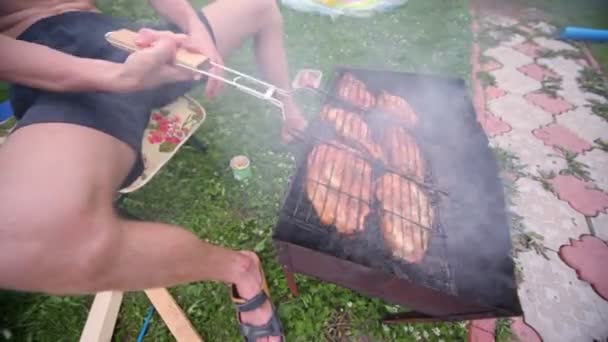 El hombre gira la rejilla con kebab en el humo de las brasas ardientes — Vídeos de Stock