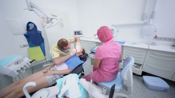 El médico realiza la cirugía en los dientes de la chica — Vídeo de stock