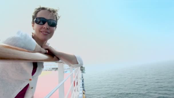 Woman stands near fence on ship and admires seascape — Stock Video