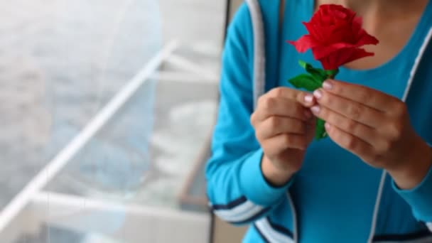 Жінка біля віконного корабля і тримає троянду з кольорового паперу — стокове відео