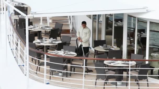 Servir dans des aspirateurs blancs plancher entre les tables sur le pont ouvert du navire — Video