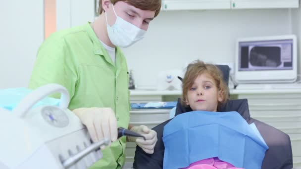 Zubař klade dentální nástroje do úst dívky v chirurgii — Stock video