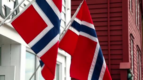 Стена здания с двумя флагами Норвегии, которые развеваются на ветру — стоковое видео