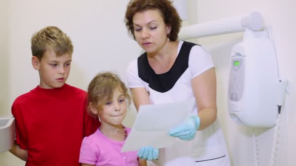 Доктор показывает рентгеновское изображение для двух детей мальчик и девочка — стоковое видео