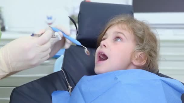 Tandarts zet tandheelkundige spiegel in meisjes mond — Stockvideo
