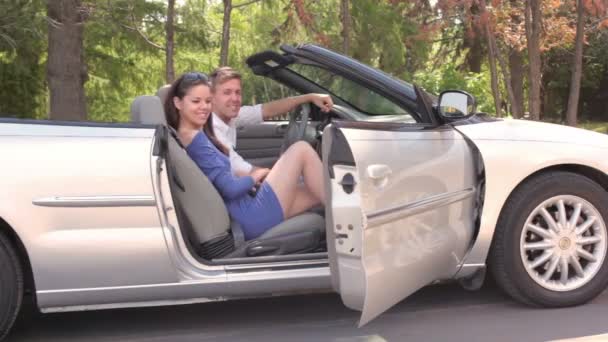 Молодая пара сидит в кабриолете и девушка закрывает дверь в летний день — стоковое видео