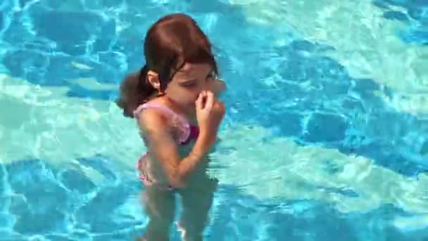 Malá holčička vrhá do vody v bazénu a plavání s mnoha stříkance