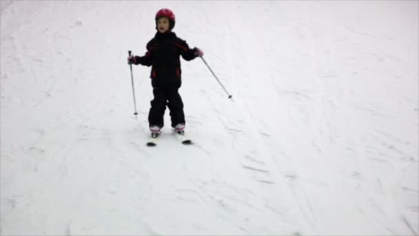 头盔，穿暖和的衣服的小女孩移动高山滑雪板 — 图库视频影像