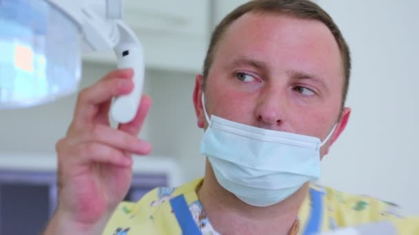 Zahnarzt bewegt Lampe und schaltet Licht ein, um Füllungen zu verfestigen — Stockvideo