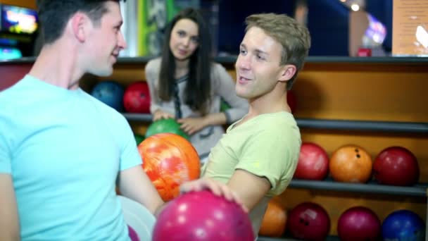 Zwei Jungs mit einem Mädchen reden und lächeln im Bowlingclub — Stockvideo