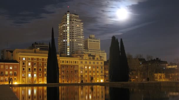 Hoogbouw gebouw staat tegen de nachtelijke hemel en zwevende wolken — Stockvideo