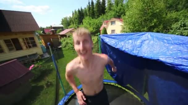 L'uomo salta e alza le mani ai lati sul trampolino — Video Stock