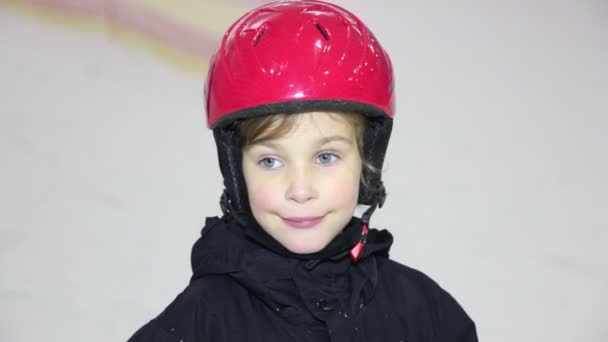 Маленькая девочка в шлеме смотрит и улыбается, мама движется на лыжах — стоковое видео